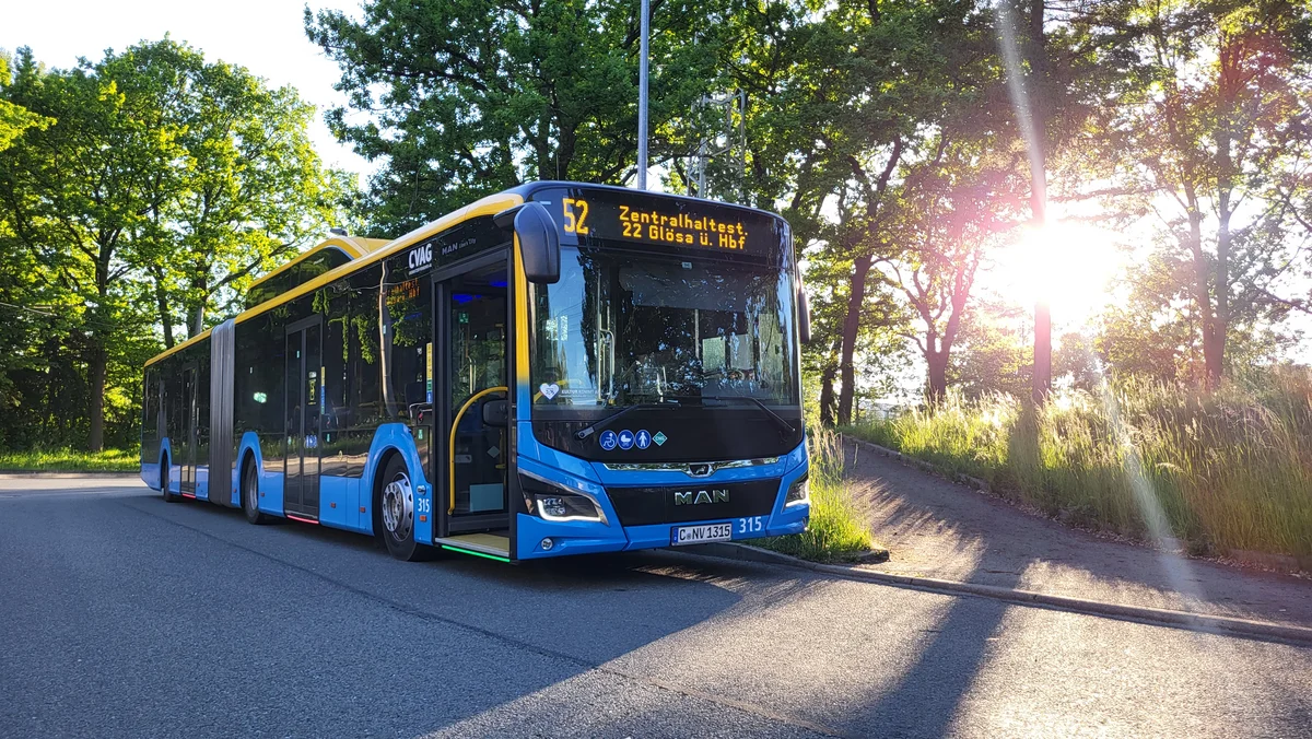 Das Bild zeigt einen CVAG Bus auf der Linie 52. Der Bus steht an einer Endhaltestelle, im Hintergrund sieht man Bäume durch die das Sonnenlicht fällt. 
