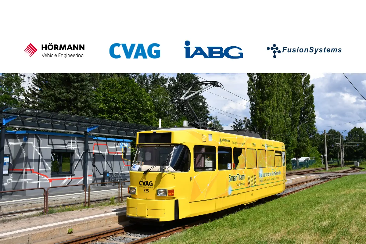 Ein gelb beklebter Tatrabahnwagen mit der Aufschrift SmarTram steht an einer Haltestelle.