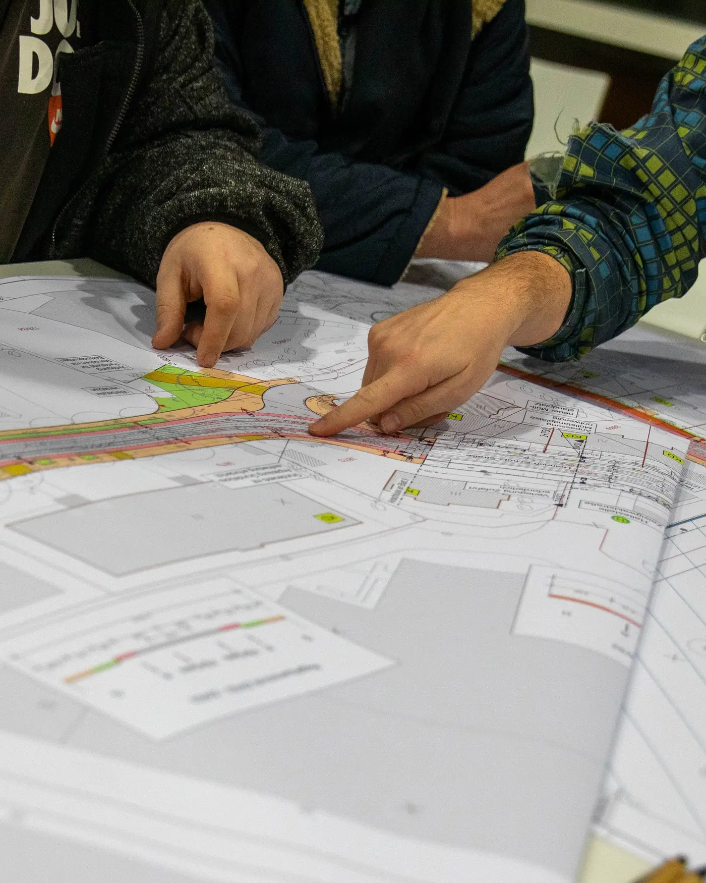 Das Bild zeigt von schräg oben fotografiert einen Lageplan der geplanten Straßenbahnneubaustrecke Zeisigwald. Zwei Personen, die im Bild nicht zu sehen sind, zeigen mit ihren Händen etwas auf dem Lageplan. 